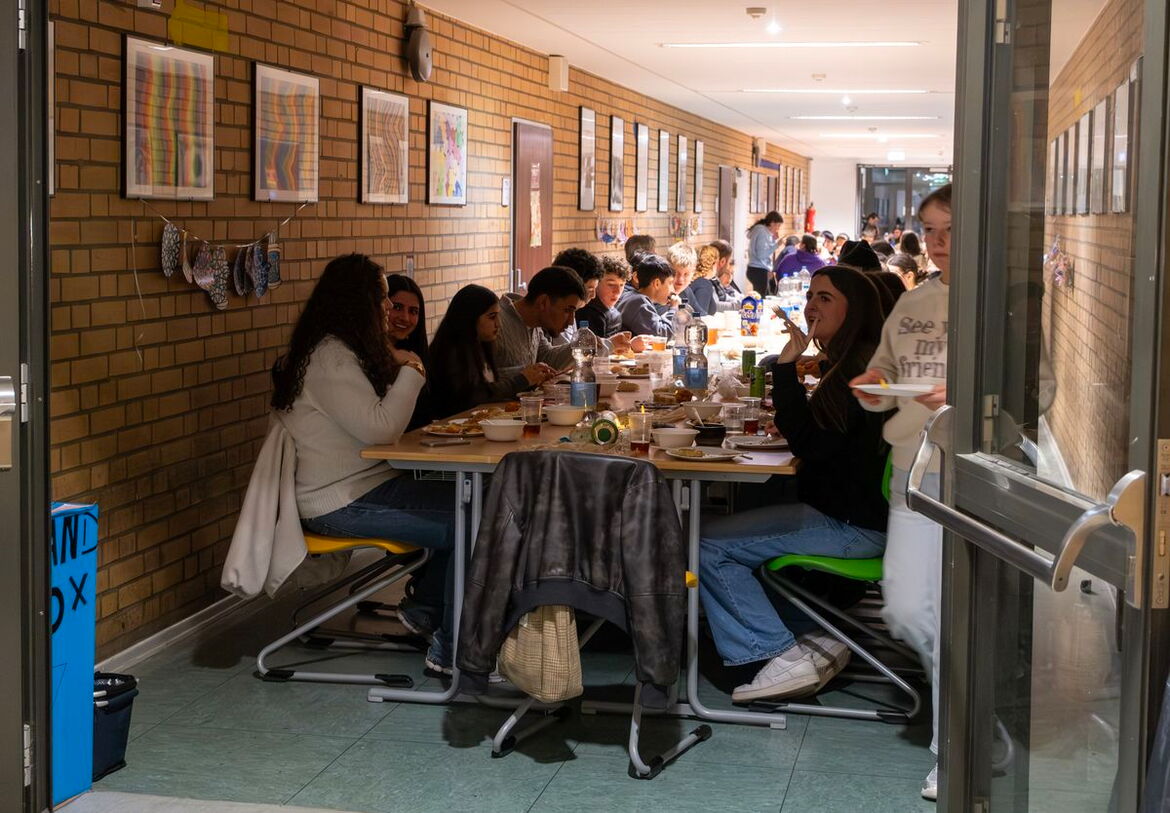 Schüler sitzen gemeinsam an einer reichlich gedeckten Tafel