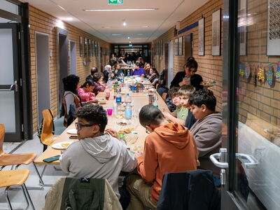 Schüler sitzen gemeinsam an einer reichlich gedeckten Tafel