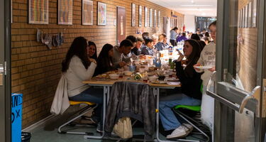 Schüler sitzen gemeinsam an einer reichlich gedeckten Tafel