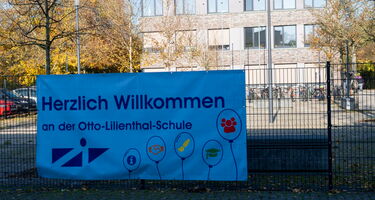 Am Zaun hängendes Plakat Herzlich willkommen