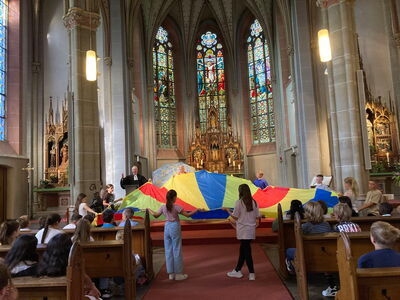 Kinder breiten vor dem Altar ein buntes Tuch aus